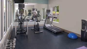 A gym with cardio machines, dumbbells, and a blue exercise ball.