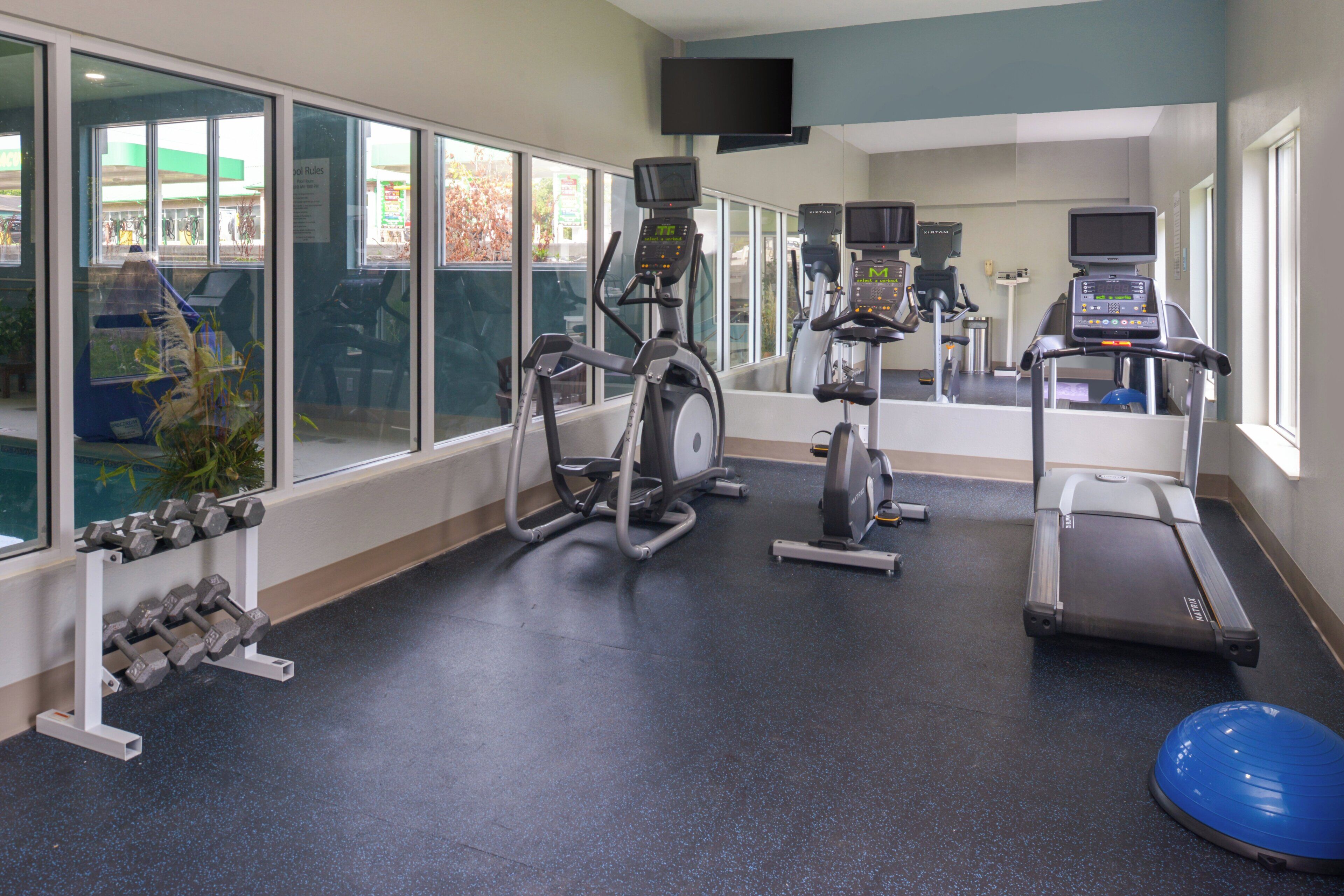 A gym with exercise equipment, including treadmills, stationary bikes, and dumbbells.
