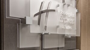 A wall with a sign for Holiday Inn Express & Suites, featuring a modern design with grey and wooden elements. - Holiday Inn Express & Suites Chattanooga (East Ridge) by IHG (Chattanooga)