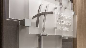 A wall with a sign for Holiday Inn Express & Suites, featuring a modern design with grey and wooden elements.