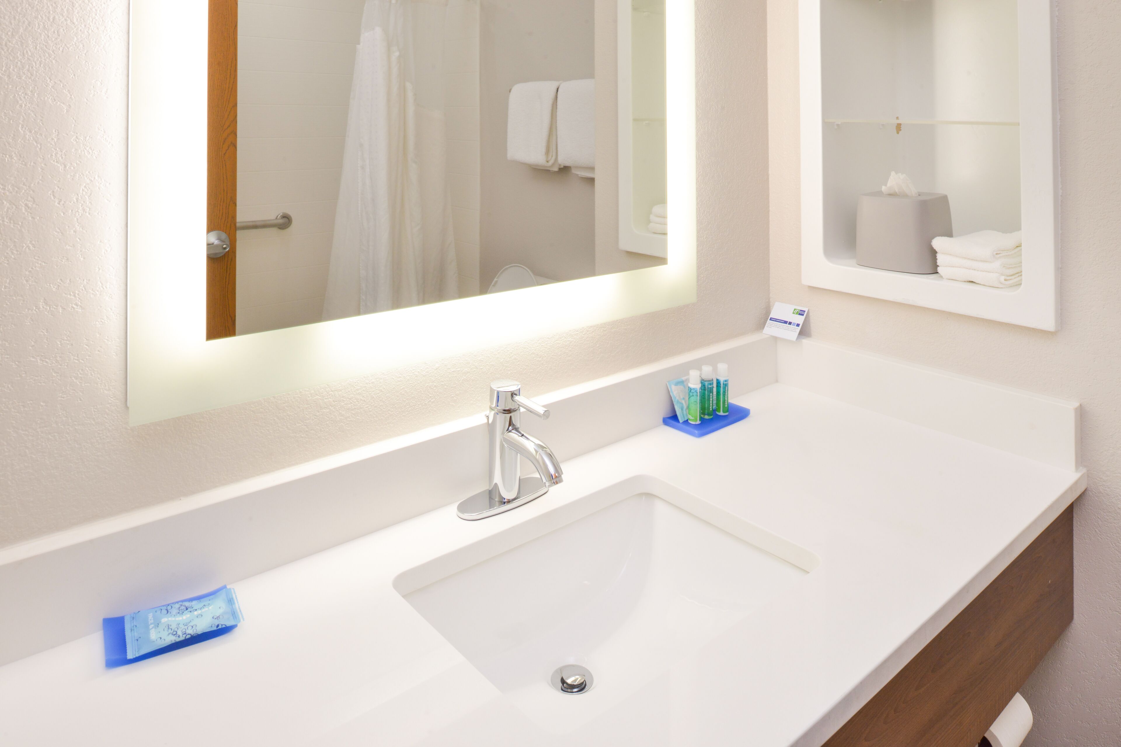 A hotel bathroom with a white sink, a mirror, and a towel rack.