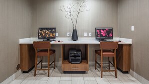 A modern office desk with two monitors, a vase with branches, and a printer. - Holiday Inn Express & Suites Chattanooga (East Ridge) by IHG (Chattanooga)
