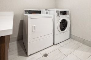 A laundry room with two white front-loading washing machines and a dryer.