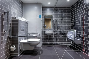 Un baño moderno con azulejos grises, un inodoro, un lavamanos y una ducha.
