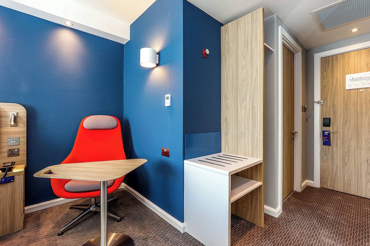 A modern room with a blue accent wall, a red chair, a wooden desk, and a built-in bench.