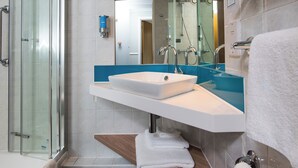 A modern bathroom with a glass shower enclosure, a white sink, and a blue countertop.
