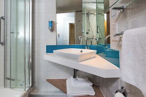A modern bathroom with a glass shower enclosure, a white sink, and a blue countertop.