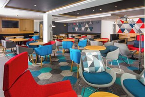 A modern interior with multiple seating areas, tables, and a flat-screen TV mounted on the wall. - Holiday Inn Express London Hammersmith by IHG (London)