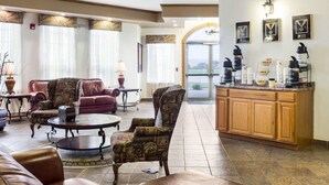 A spacious living area with leather sofas, patterned armchairs, and a coffee station.