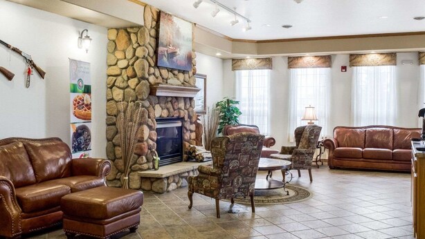 A spacious living room with a stone fireplace, leather sofas, patterned armchairs, and a television.