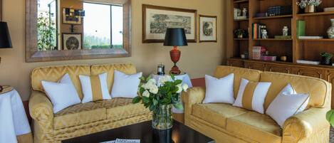 A living room with two sofas, a coffee table, a bookshelf, and framed artwork on the wall.