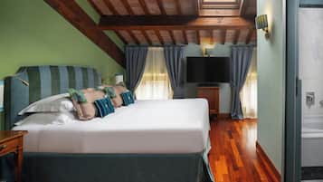 Quarto com cama grande, televisão, teto de madeira e porta de banheiro.