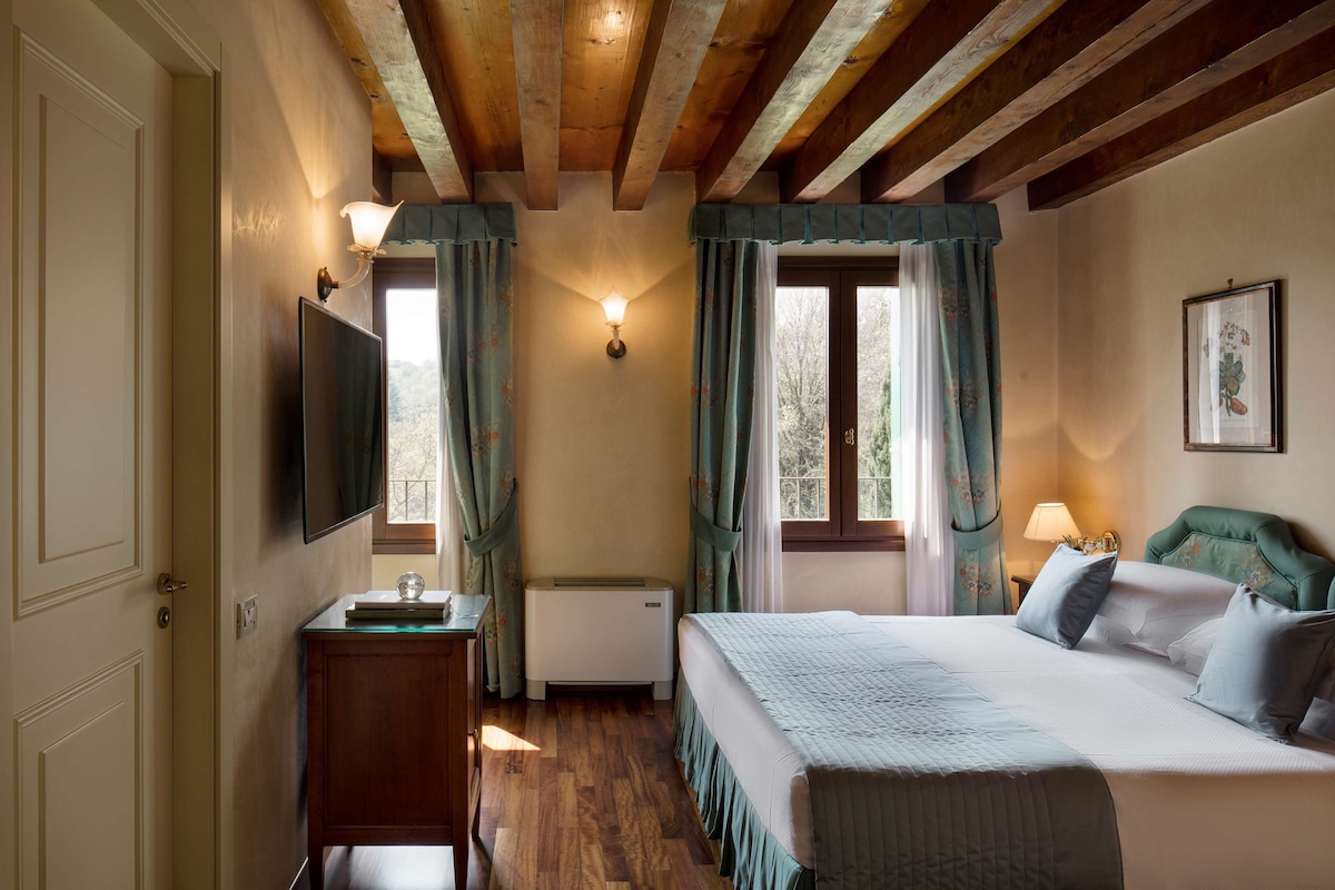 Un dormitorio con cama, televisión, calefactor y ventana con cortinas.