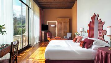 A hotel room with a large bed, a television, a desk, and a view of the outdoors.