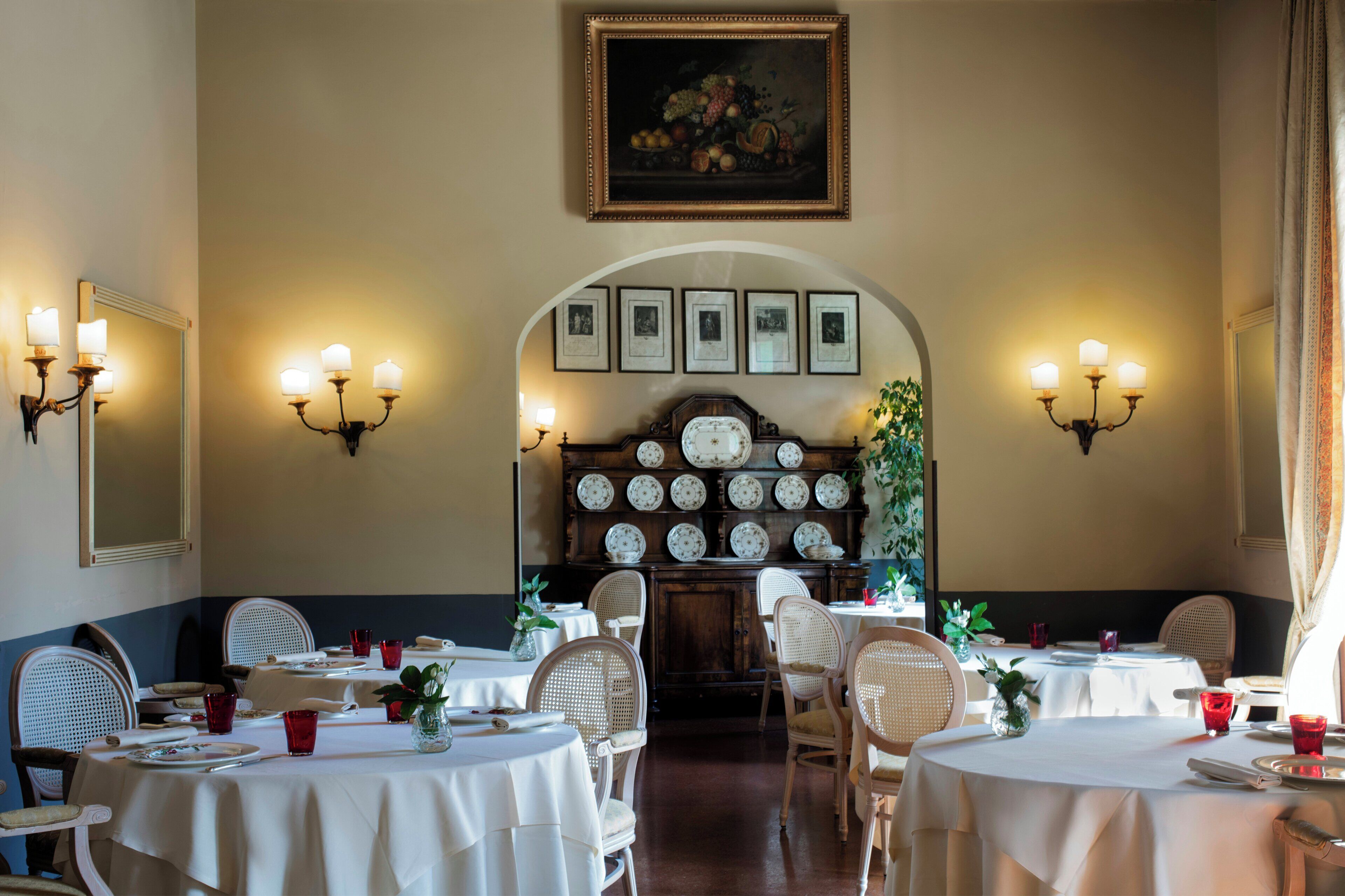 A dining area with tables, chairs, and wall-mounted lighting.