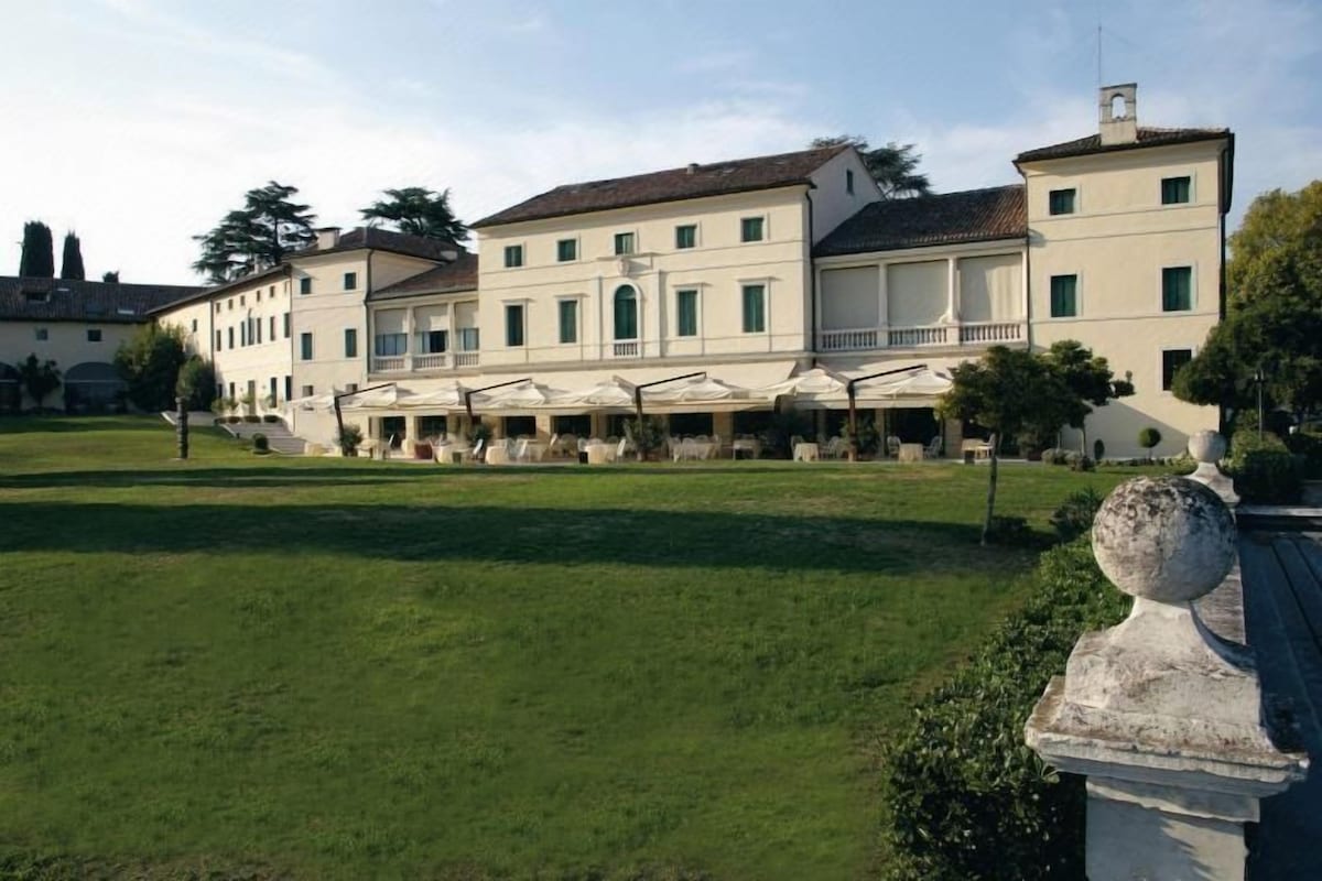 A large building with multiple floors, a central courtyard, and outdoor seating areas.
