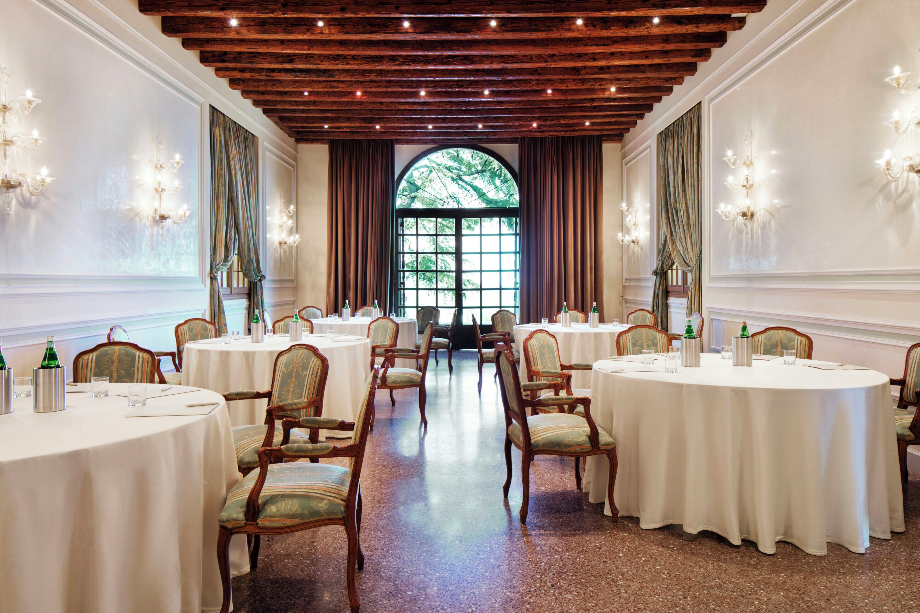 Une salle à manger élégante, avec des tables rondes, des chaises et des lustres.
