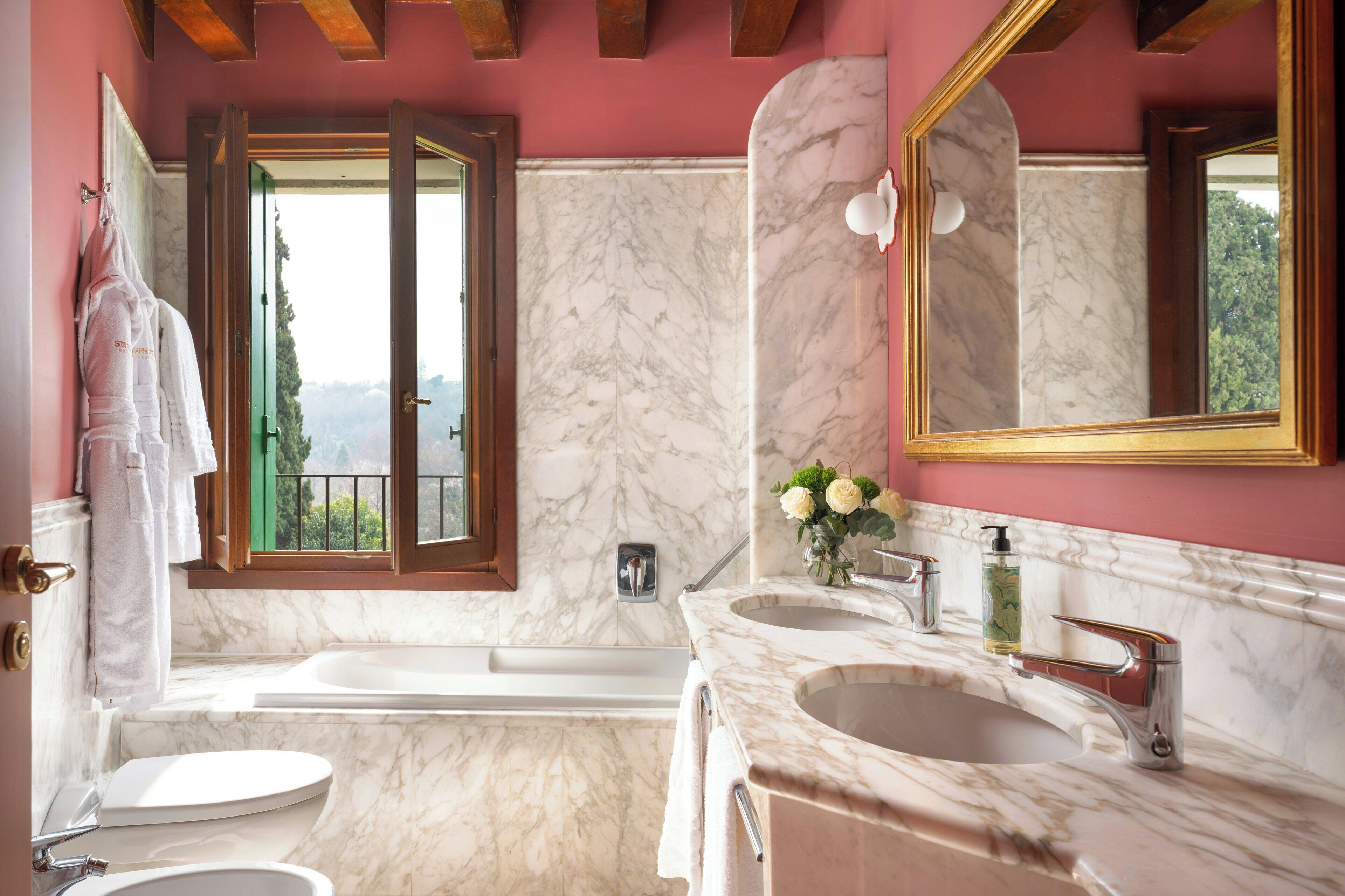 A bathroom with a bathtub, two sinks, a toilet, and a large mirror.