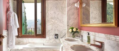 A bathroom with a bathtub, two sinks, a toilet, and a large mirror.
