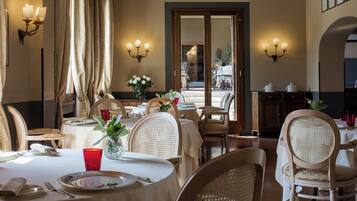 Comedor con mesas dispuestas para dos, con sillas de mimbre y manteles blancos.