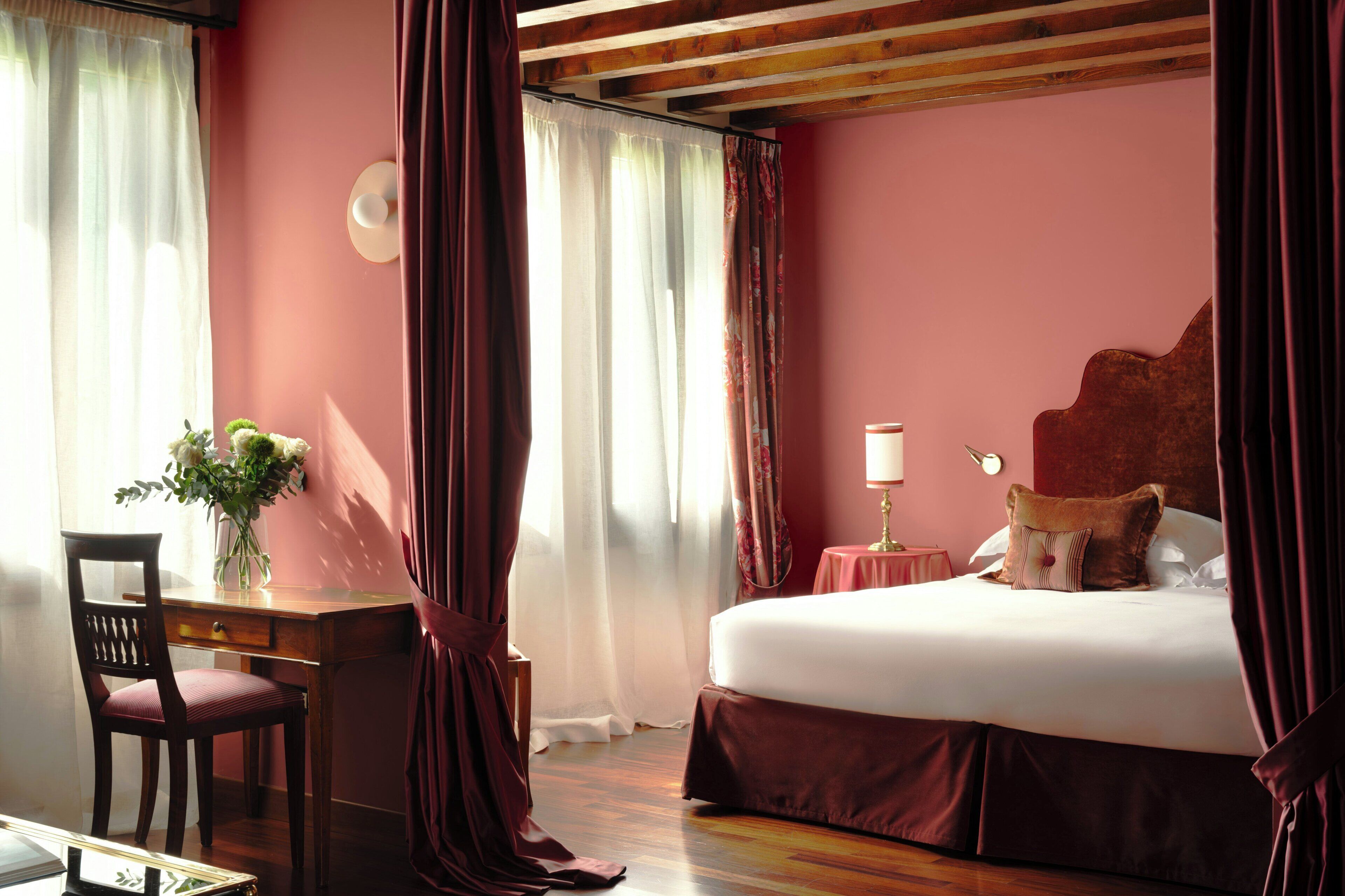A bedroom with a bed, a desk, a chair, and a vase of flowers.