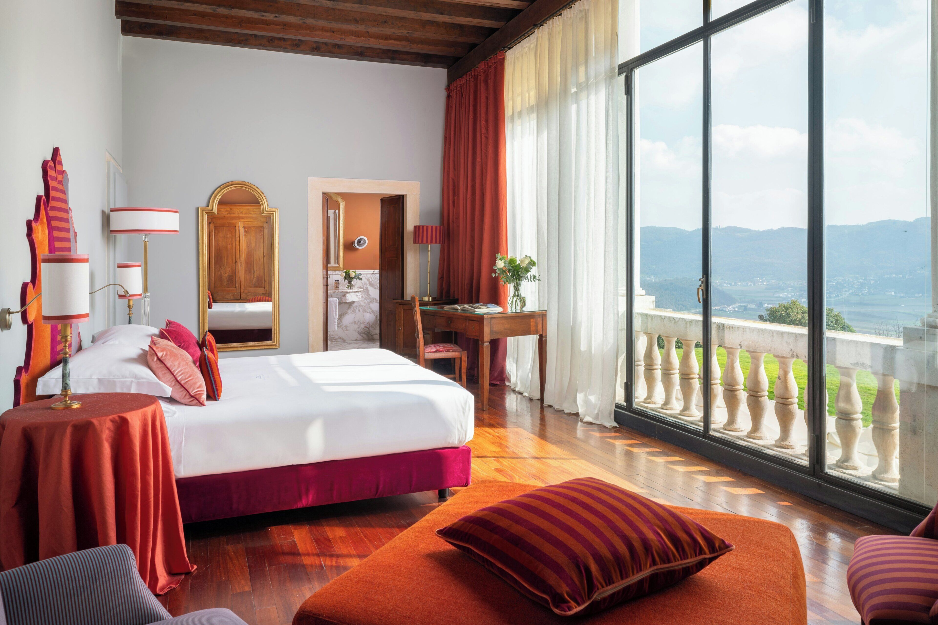 Ein Hotelzimmer mit einem großen Bett, einem Schreibtisch, einem Sessel, einem Tisch und Blick auf die Landschaft.