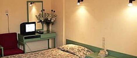A room with two beds, a desk with a computer, a mirror, and a red chair.