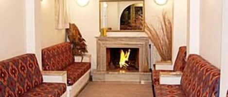 A living room with patterned sofas, a fireplace, and a mirror on the wall.