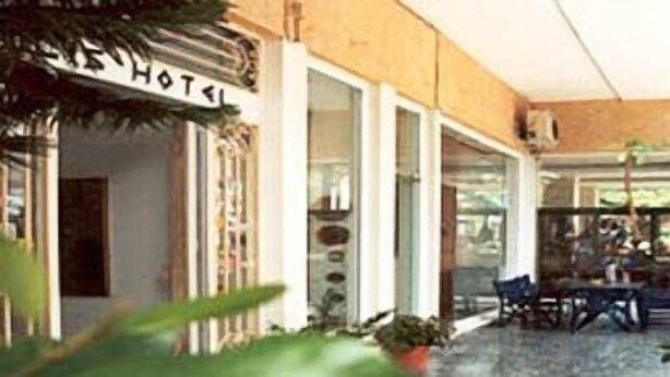 A hotel lobby with a stone floor, a reception desk, and a sign indicating the hotel name.