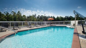 A swimming pool with a white fence, lounge chairs, and an umbrella. - Hampton Inn Cornelia (Cornelia)