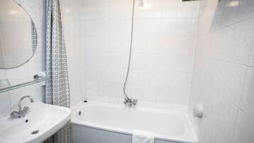 Un baño con un lavamanos blanco, una bañera y una ducha.