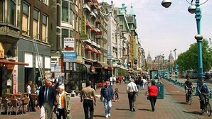A busy street with pedestrians, cyclists, and various shops. - Delta Hotel City Center (Amsterdam)