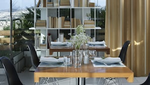 Ett matbord dukat med tallrikar, glas och en vas med blommor, med en bokhylla i bakgrunden.