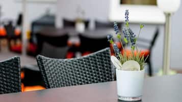 Una mesa de comedor con una taza blanca que contiene una planta y un vaso.
