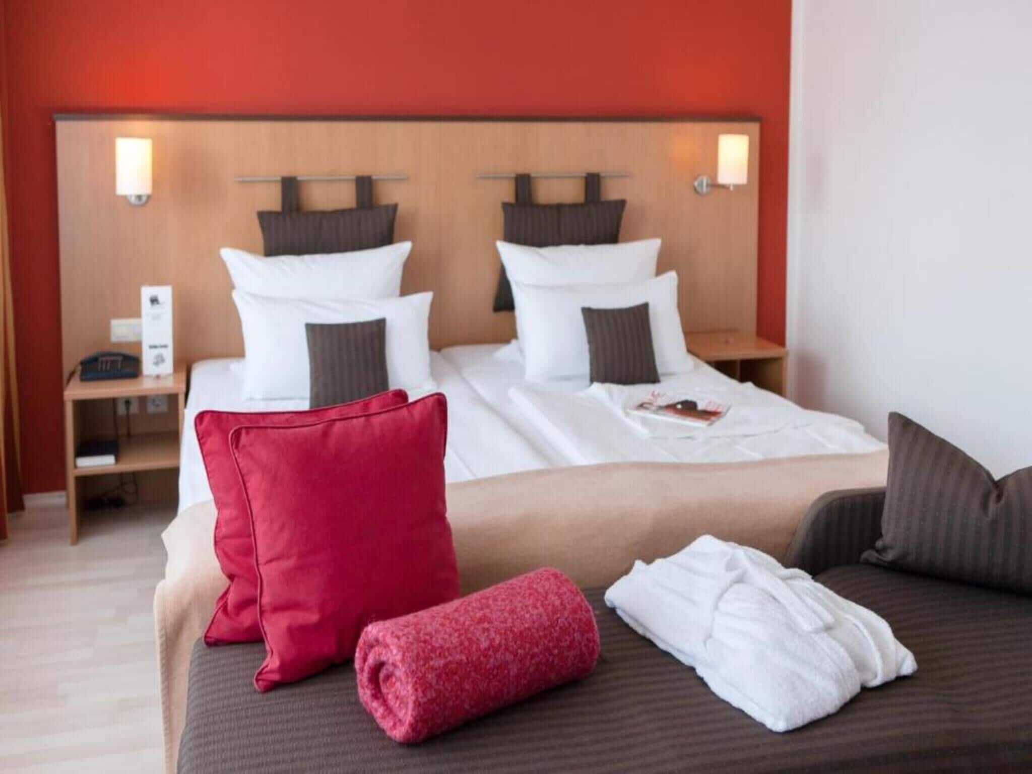 Habitació d'hotel amb un llit gran, dues taules de nit i un capçal de llit amb làmpades penjades a la paret.
