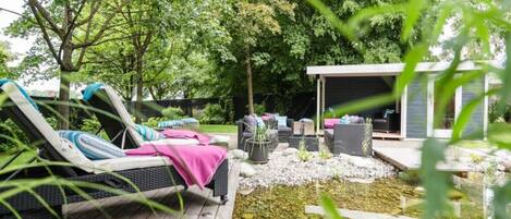 A deck with lounge chairs and a small pond.