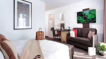 Ein Hotelzimmer mit Bett, Schreibtisch, Sofa, Fernseher und Fenster.