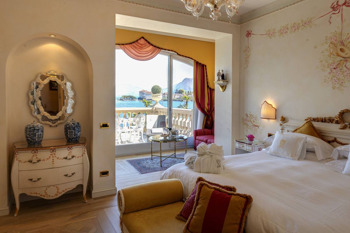 A hotel room with a bed, a dresser, a mirror, and a view of the sea.
