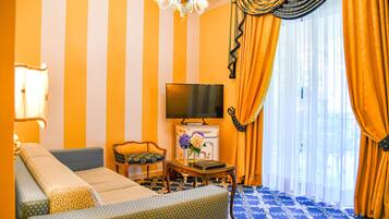 A room with a sofa, a television, and a table with a vase of flowers.