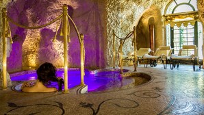 A spa area with a pool, stone walls, and lounge chairs.