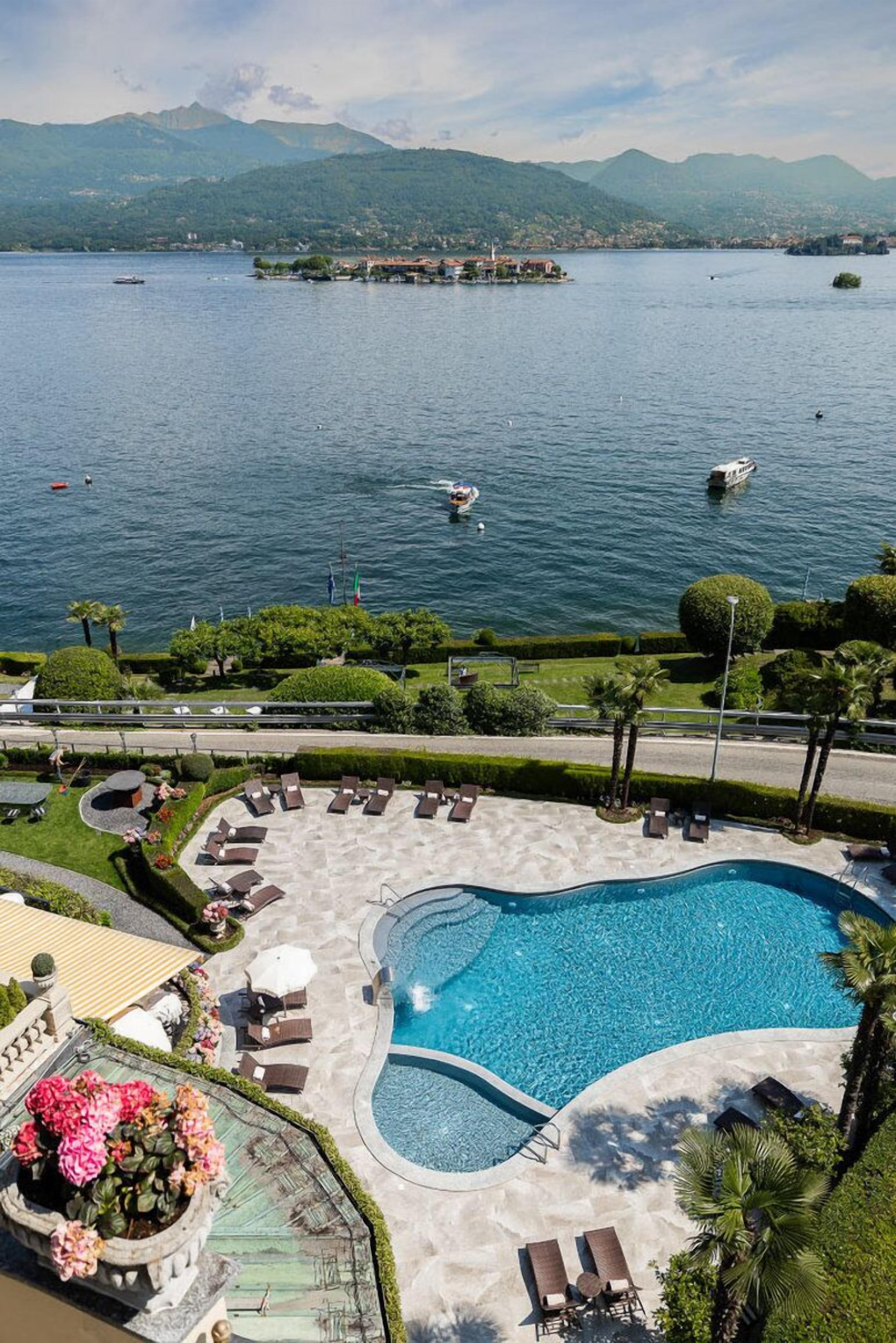 Una piscina con sillas de descanso y vistas a un lago con barcos.