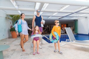 A poolside area with a clear view of the pool, lounge chairs, and a covered walkway.