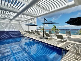 Una piscina al aire libre, sillones reclinables de piscina