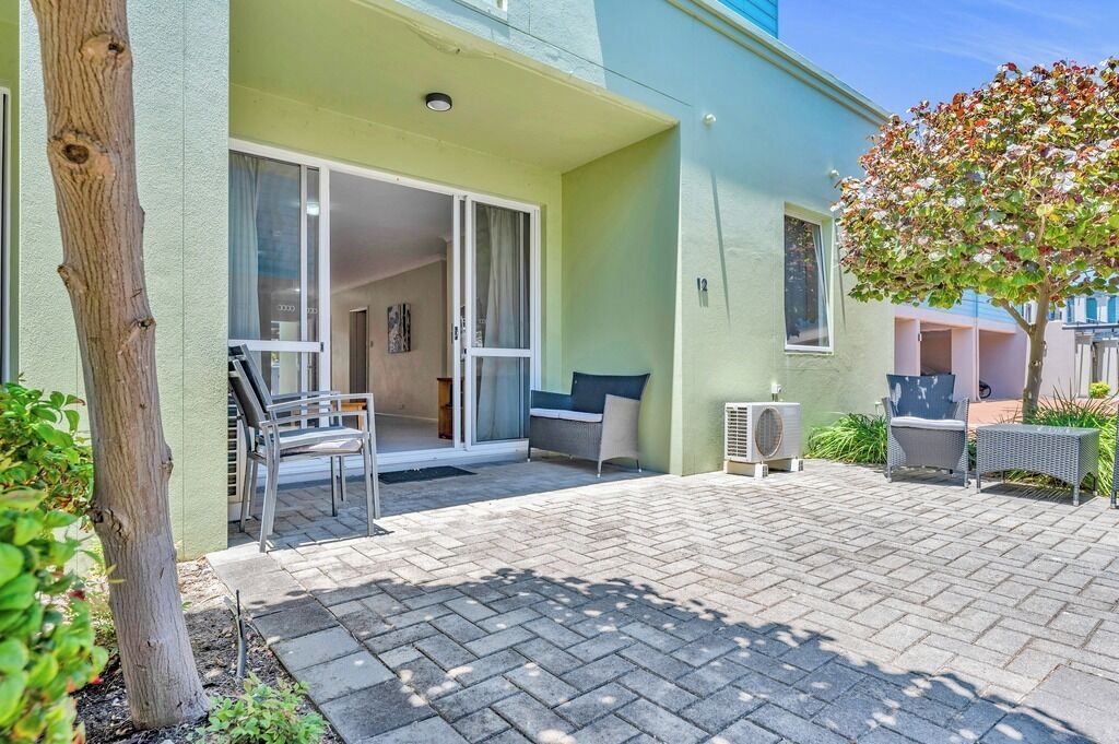 A residential building with a patio area, a sliding glass door entrance, and outdoor furniture.