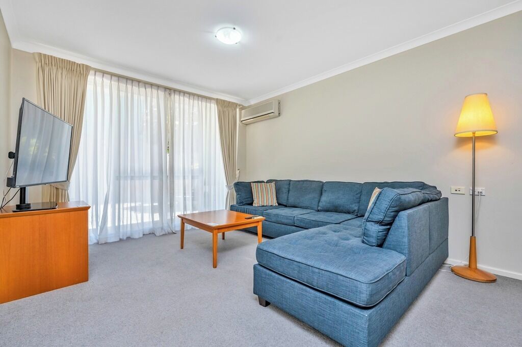 A living room with a sofa, a coffee table, a TV on a stand, and a lamp.