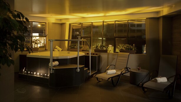 A modern spa room with a hot tub, two lounge chairs, and large windows. - Casa Grande Suites (La Paz)