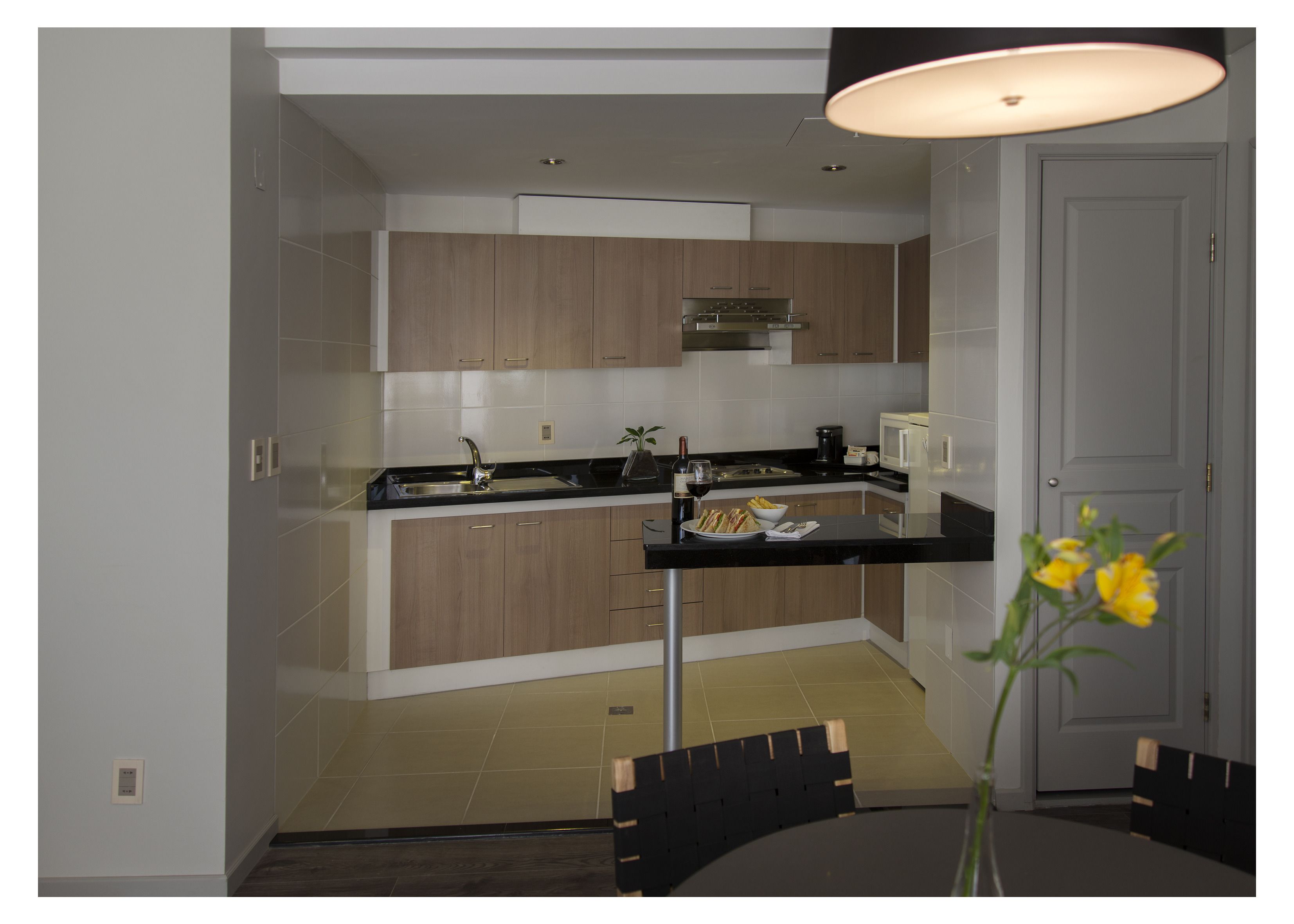 A modern kitchen with wooden cabinets, a black countertop, and a dining area with a table and chairs.