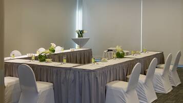 A conference room with a long table, white chairs, and a small decorative plant.