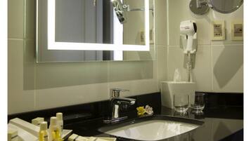 Un baño moderno con un espejo grande, un lavamanos y un secador de pelo.