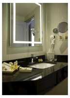Un baño moderno con un espejo grande, un lavamanos y un secador de pelo.